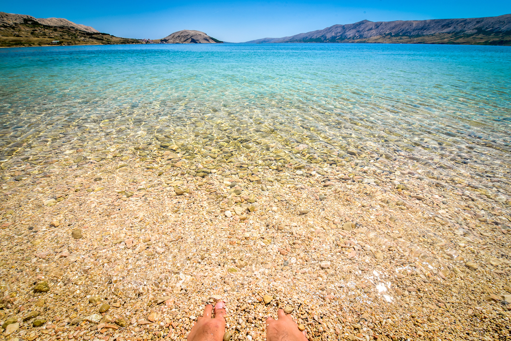 Feet legs in the sea or ocean. Beach in the coast of Adriatic Sea island Pag or Hvar