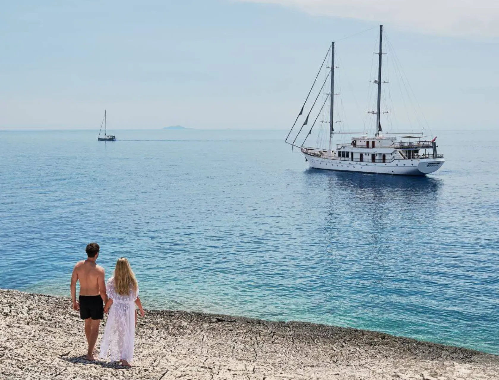 Luxury gulet charter in the view of a young couple standing on a beach