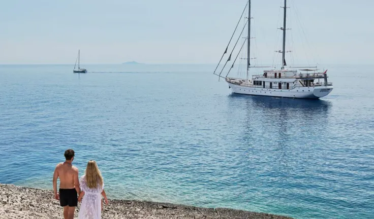 Luxury gulet charter in the view of a young couple standing on a beach